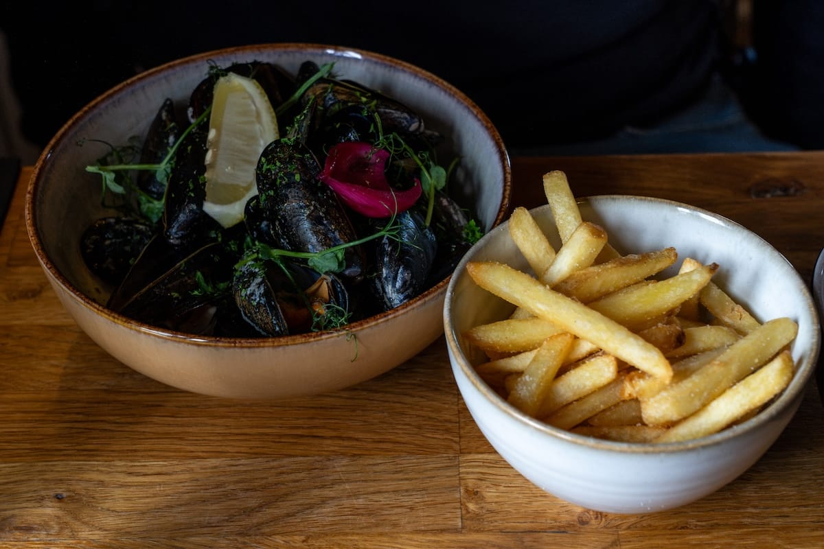 a bowl of mussels with a side of french fries at a restaurant in norway