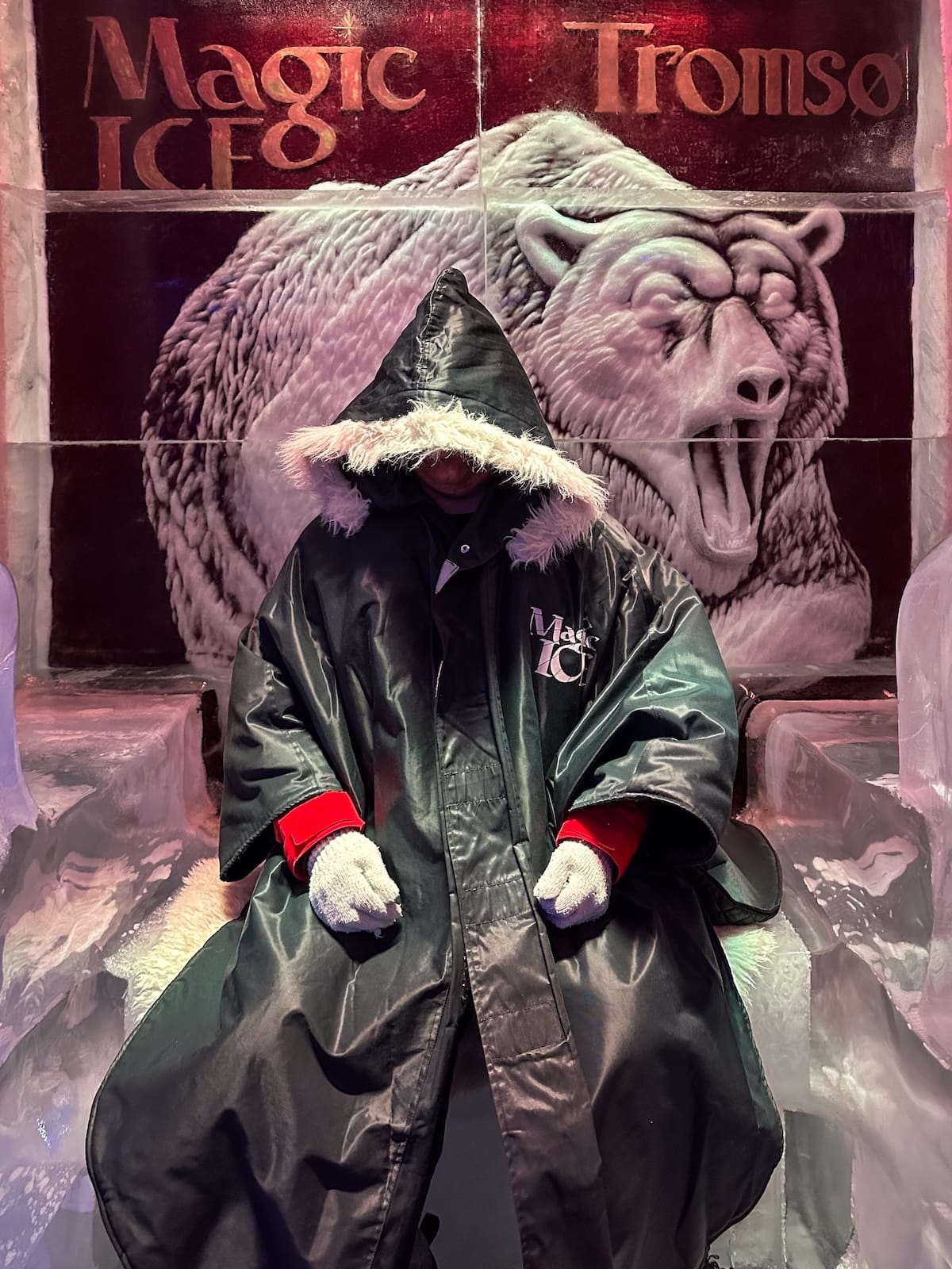 a man sitting in a hooded parka inside an ice bar