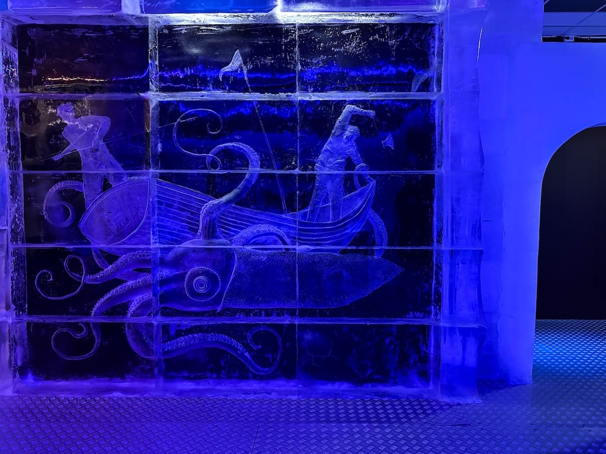 a very blue photo inside an ice bar with artwork on the walls made of ice