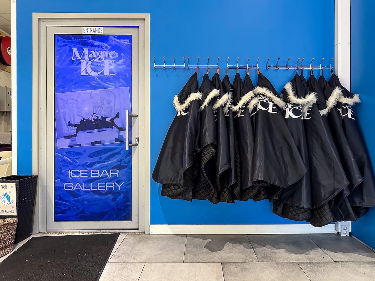 a rack of parkas beside the entrance into an ice bar